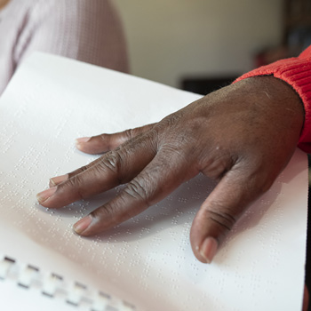 Close up of a hand reading a Braille book.